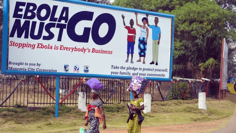 Two women walk in front of an Ebola must go billboard in Monrovia, Liberia